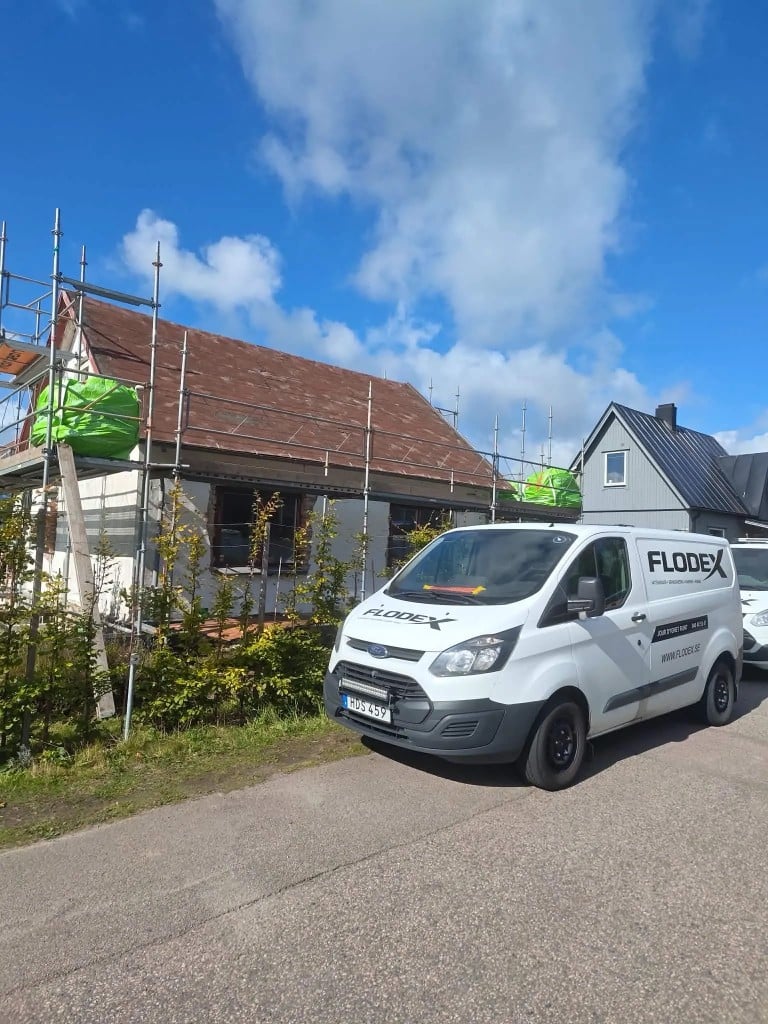 Flodex servicebil parkerad vid villa med byggställning och takarbete i Skåne