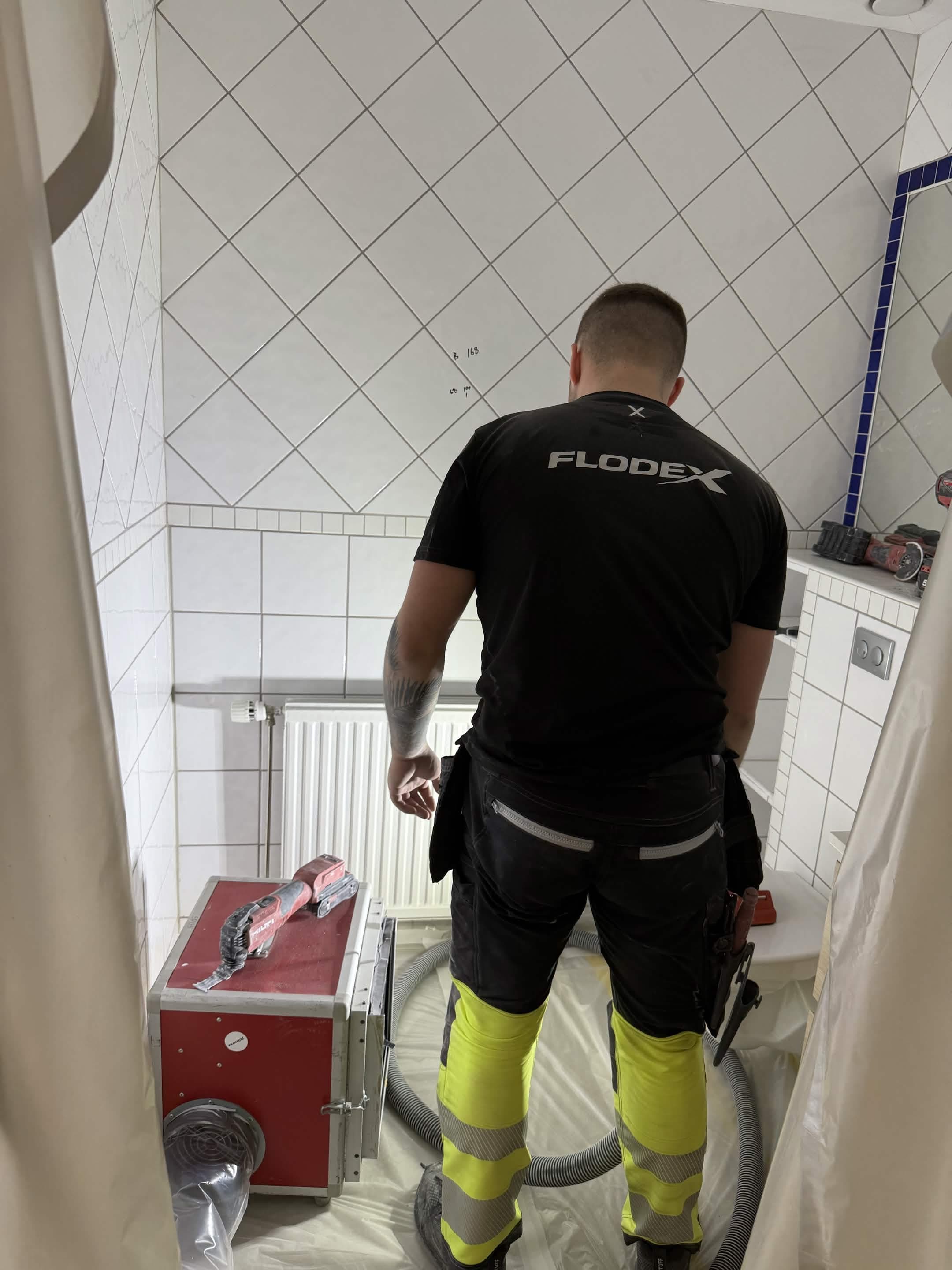 Flodex-personal i skyddsutrustning förbereder badrum med plastskydd, dammsugning och rätt utrustning vid inomhusuppdrag